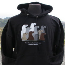 Load image into Gallery viewer, Black hooded sweatshirt featuring design with 10 sea lion profiles in white, gray, tan, and brown on front. Text "The Marine Mammal Center Sausalito, California" beneath image.
