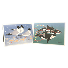 Load image into Gallery viewer, 2 holiday cards: 3 gulls standing among red and yellow stars, and 3 orcas swimming in green water trailing red streamers and yellow stars.