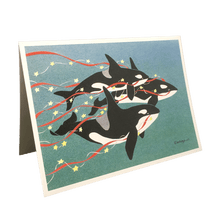 Load image into Gallery viewer, Holiday card with 3 orcas swimming against green-blue background, carrying red streamers and yellow stars.