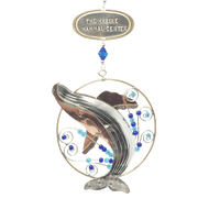 Silver and tan-colored metal ornament in shape of breaching humpback whale in a thin circular frame, with blue beads. Oval-shaped metal tag on top reads 