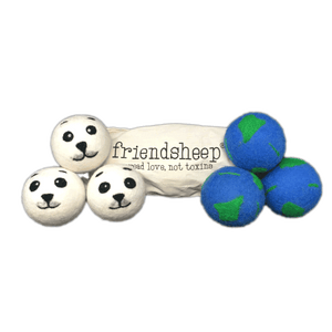 Two sets of three dryer balls in front of cream-colored bag that reads "friendship, spread love, not toxins". Dryer balls on left side are white with baby seal face design felted on in black and gray. Dryer balls on right are blue with green patches felted on to represent Planet Earth. 