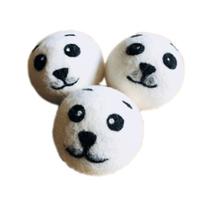 Load image into Gallery viewer, 3 white wool dryer balls with seal faces felted on in black. 

