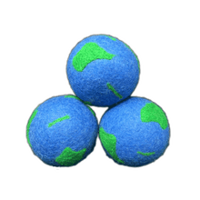 Load image into Gallery viewer, Three blue dryer balls with green patches, resembling Planet Earth. 
