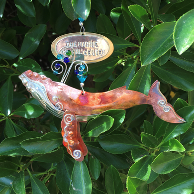 Copper and silver-colored metal humpback whale ornament with blue and white beads. Oval metal hangtag on hanger reads 