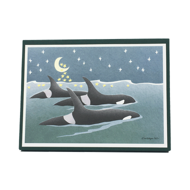 Box of holiday cards with three orcas swimming at the surface of the sea. The moon and stars in the night sky are reflected on the water's surface.