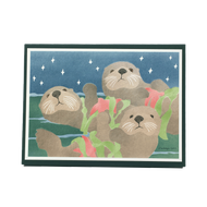 Box of holiday cards featuring three sea otters floating on ocean surface, each holding a red sea star and fronds of green kelp. 