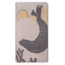 Load image into Gallery viewer, Coral-colored beach towel with dark gray harbor seal silhouette and yellow sunrise design. White tassel fringe along top and bottom
