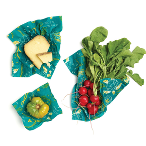 3 ocean-patterned beeswax wraps containing cheese, a bell pepper, and red radishes.