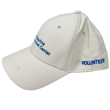 Load image into Gallery viewer, Khaki baseball cap with blue embroidery of the logo on the front and &#39;volunteer&#39; on the side.
