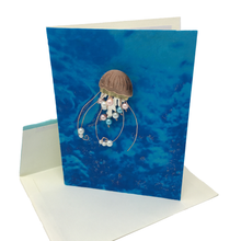 Load image into Gallery viewer, Blank greeting card with metal sea jelly pin attached to blue front cover. 
