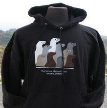Load image into Gallery viewer, Black hooded sweatshirt featuring design with 10 sea lion profiles in white, gray, tan, and brown on front. Text &quot;The Marine Mammal Center Sausalito, California&quot; beneath image.

