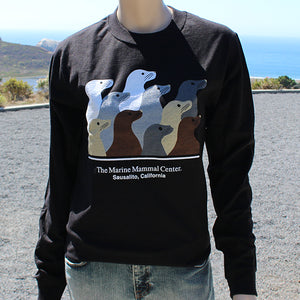 Black long-sleeve shirt with ten sea lions design, on full-size mannequin against coastline background
