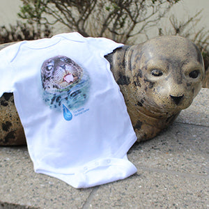 White infant onesie with a harbor seal's face and TMMC's logo draped over a harbor seal statue.