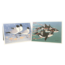 Load image into Gallery viewer, 2 holiday cards: 3 gulls standing among red and yellow stars, and 3 orcas swimming in green water trailing red streamers and yellow stars.
