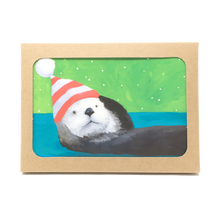 Load image into Gallery viewer, Box of holiday cards with sea otter wearing striped hat on cover.
