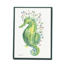 Load image into Gallery viewer, Holiday card box cover with green seahorse carrying a string of multi-colored holiday lights.
