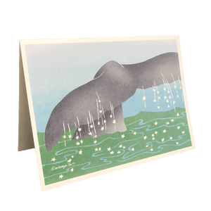 Holiday card with whale tail emerging from green water dotted with white stars.