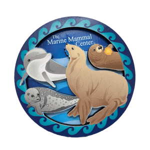 Blue magnet depicting several species of marine mammals, including a seal and sea otter, with TMMC name.