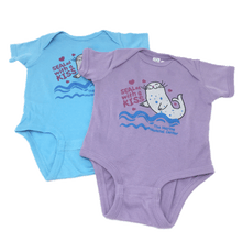 Load image into Gallery viewer, Purple and Blue &quot;Sealed with a Kiss&quot; onesies with The Marine Mammal Center name, depicting a cartoon seal grey with blue spots, small magenta hearts around the design, and blue wavey lines under the seal. The purple onesie is laying out flat slightly overlapping the blue onesie also laying out flat.
