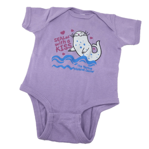 Purple onesie with The Marine Mammal Center name, depicting a cartoon seal grey with blue spots, small magenta hearts around the design, and blue wavey lines under the seal.
