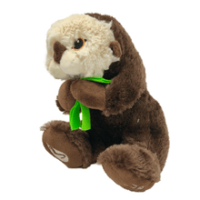 Load image into Gallery viewer, Plush brown and light tan sea otter with embroidered eyes holding bright green kelp. Embroidered feet show white The Marine Mammal Center name and logo in white thread. 
