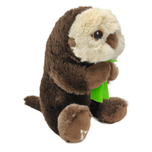 Load image into Gallery viewer, Plush brown and light tan sea otter with embroidered eyes holding bright green kelp. Embroidered feet show white The Marine Mammal Center name and logo in white thread. 
