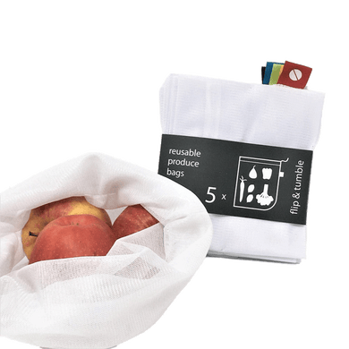 A white mesh reusable produce bag holding fruit produce apples in the foreground. A 5-pack of white mesh reusable produce bags squarely folded in black packaging with white lettering sits behind.