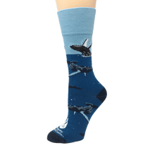 Load image into Gallery viewer, Blue socks with light blue cuff, dark blue heel and toe, and swimming and breaching humpback whale illustrations. The Marine Mammal Center&#39;s logo in white above toe.
