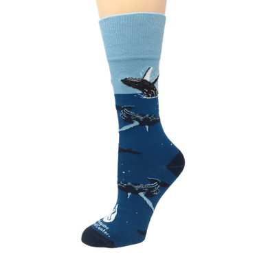 Blue socks with light blue cuff, dark blue heel and toe, and swimming and breaching humpback whale illustrations. The Marine Mammal Center's logo in white above toe.