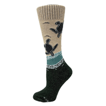 Load image into Gallery viewer, Crew-length sock on a mannequin foot with design of baby sea turtles entering the ocean from the beach. Tan upper half and forest-green lower half.
