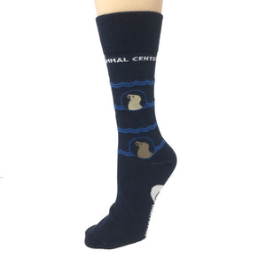 Deep blue TMMC logo sock on a foot mannequin, where sea lions in profile amongst waves are visible along the ankle-calf portion of the sock.  TMMC  logo is on the instep-bottom of the sock, and "The Marine Mammal Center" encircles the calf.