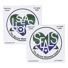 Load image into Gallery viewer, Two circular stickers, each with a blue and green heart design containing white letters reading &quot;SEA LIONS&quot; and &quot;SEALS&quot; respectively and &quot;The Marine Mammal Center&quot; beneath. 
