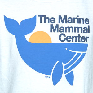 Closeup of tank top design: blue whale in front of rising sun, with text "The Marine Mammal Center" above and brand name "CULK" in small letters below whale image