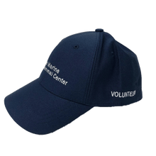 Load image into Gallery viewer, Blue baseball cap with white embroidery of the logo on the front and &#39;volunteer&#39; on the side.
