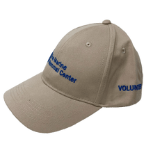 Load image into Gallery viewer, Khaki baseball cap with blue embroidery of the logo on the front and &#39;volunteer&#39; on the side.
