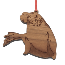 Load image into Gallery viewer, 2D laser-cut wood elephant seal ornament hanging from red ribbon.

