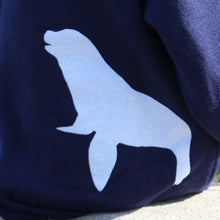 Load image into Gallery viewer, Back of a navy youth hoodie with white sea lion silhouette on bottom back right of hoodie.
