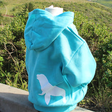 Load image into Gallery viewer, Back of a turquoise youth hoodie with white sea lion silhouette on bottom back right of hoodie. Hoodie is on a child mannequin situated in front of a coastal background.
